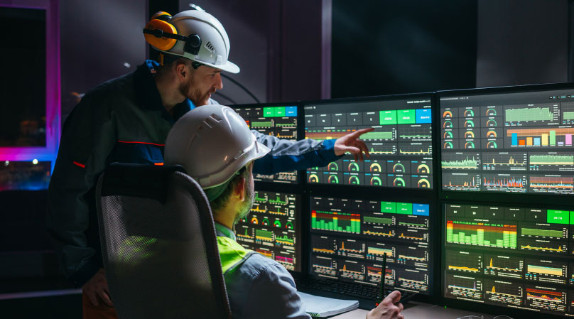 Two engineers review several control screens.